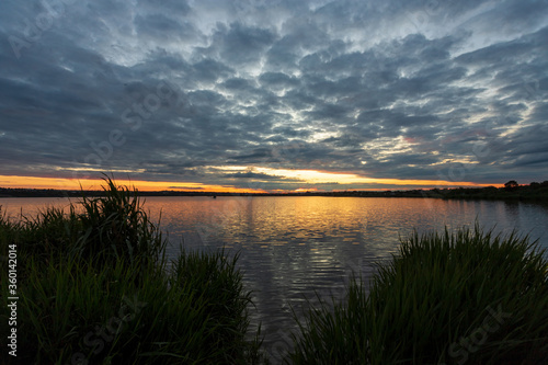 Beautiful sunrise on the river, before sunrise, with part of the shore and reeds