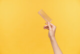 Indoor shot of young pretty woman's hand raising up wooden hairbrush while posing over orange background, young woman going out and making hairdo