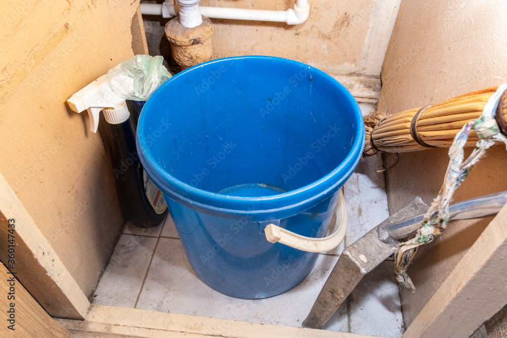 Empty dirty plastic trash garbage bin under kiitchen sink with different household goods in a house of a person with hoarding disorder Empty dirty plastic trash garbage bin under kiitchen sink with different household goods in a house of a person with hoarding disorder
