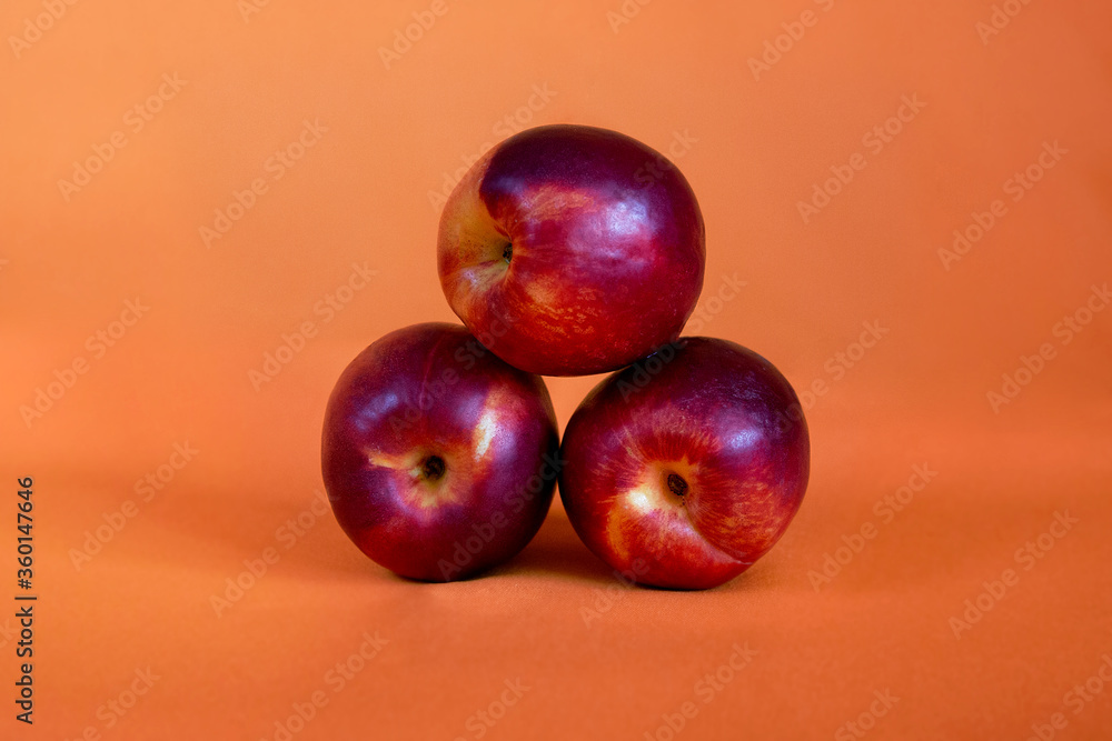 red nectarines or peaches on an orange background red nectarines or peaches on an orange background