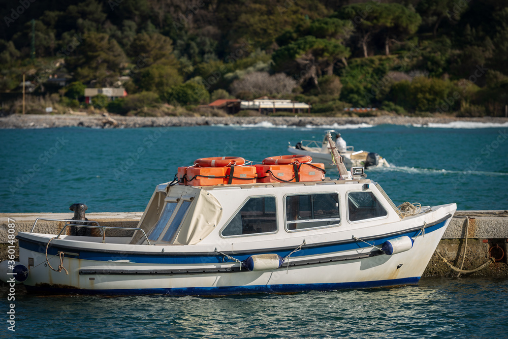 Small white and blue motor boat with orange lifebelts on the top, moored in the port of Portovenere or Porto Venere. La Spezia, Liguria, Italy, Europe