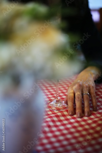 A happily married woman's hand with a wedding ring on and a glass of white wine