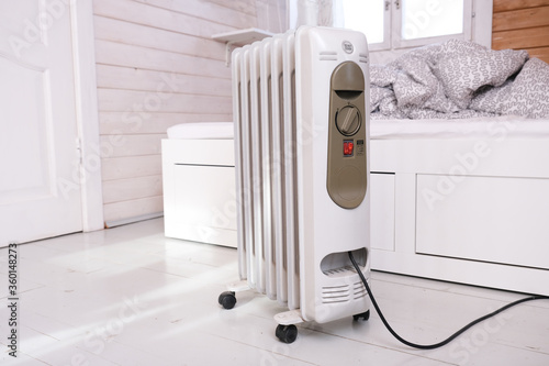 Oil-filled electrical mobile radiator heater for home heating and comfort control in the room in a wooden country house