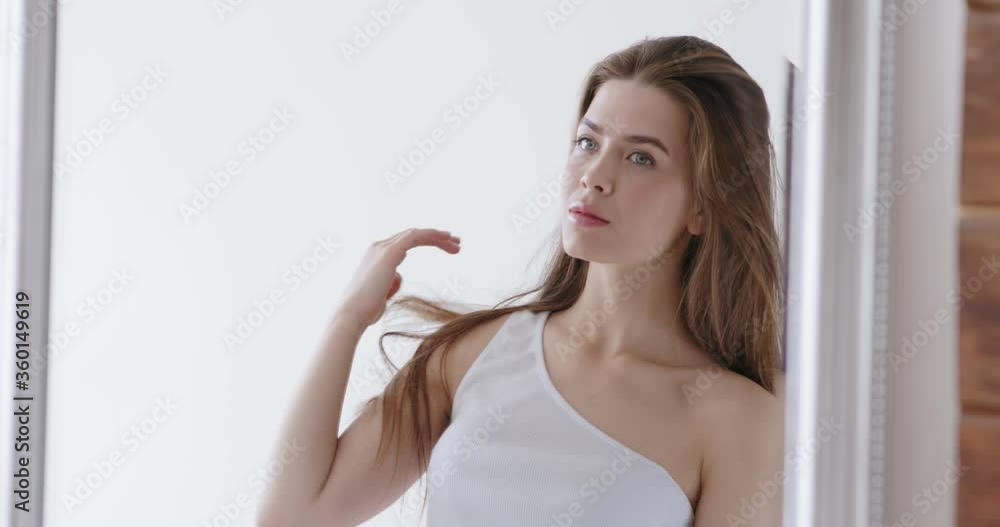 Young woman looking into mirror, preening herself Young woman looking into mirror, preening herself