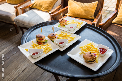 
Four plates with burgers and fries on the festive table.