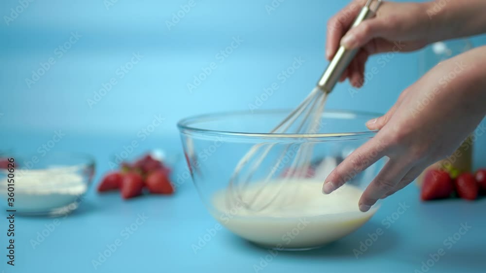 Whisking food ingredients in a big glass bowl. Whisking egg, flour, sugar, salt, oil. Close-up of a woman's hand whisking different ingredients. Concept of giving a good whisk to the ingredients. Whisking food ingredients in a big glass bowl. Whisking egg, flour, sugar, salt, oil. Close-up of a woman's hand whisking different ingredients. Concept of giving a good whisk to the ingredients.