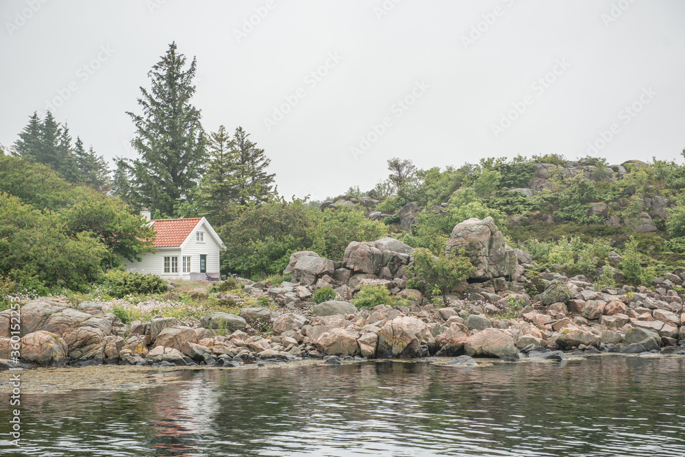 White summer house on a small island. Rocky cliffs all around