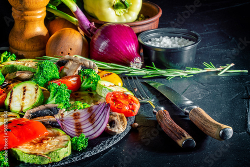 Grilled vegetables and mushrooms with basil and dry herbs on a dark background. Vegan grill concept