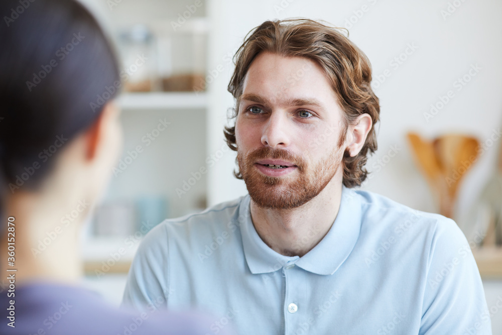 Young man talking to young woman while they sitting in the room