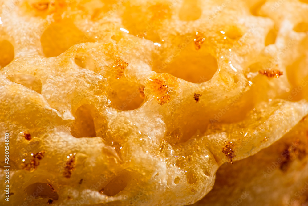 Macro photo of a toasted crumpet with honey Macro photo of a toasted crumpet with honey