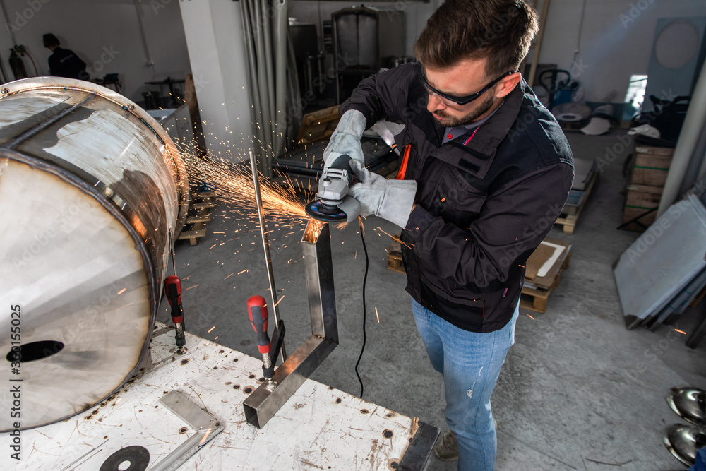 Industrial worker with angle grinder working and polishing metal structure at workshop. Industrial worker with angle grinder working and polishing metal structure at workshop.