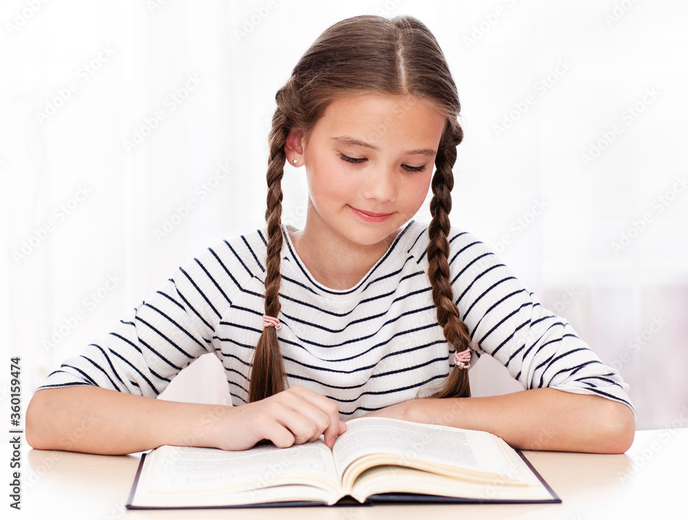 Education and school concept. Child is sitting at the desk and reading a book Education and school concept. Child is sitting at the desk and reading a book