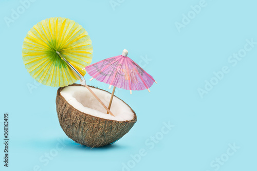 Wallpaper Mural Coco sobre fondo celeste liso y aislado con una sombrilla. Vista de frente y de cerca. Copy space. Concepto: Vacaciones Torontodigital.ca