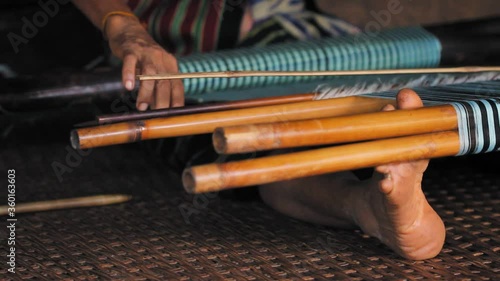 Laos, Pakse. Hands and feet of woman weaving in a traditional backstrap loom. photo