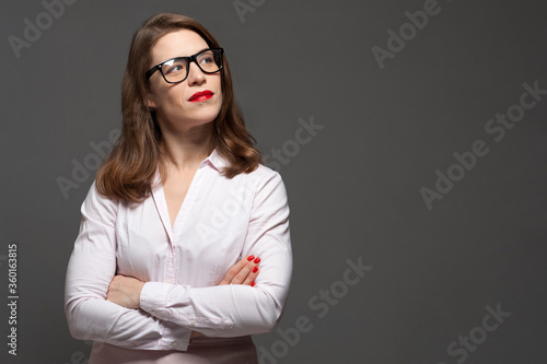 Business woman posing over grey background with crossed arms.