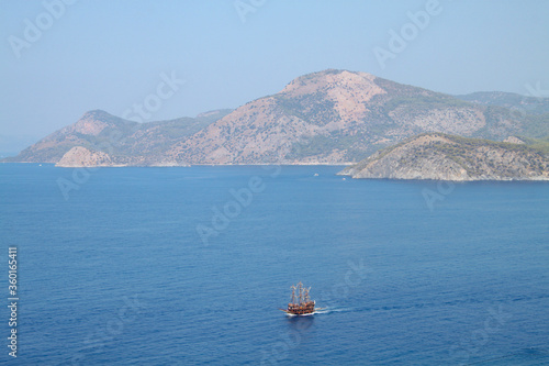 A pirate ship travels through the Mediterranean Sea, a tourist ship route, the southern coast of Turkey, a beach in Oludeniz, Mugla, Fethiye. Top view, highlands © Vi SunJu