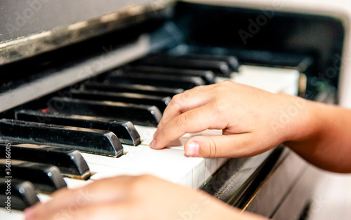 Close up of a little student's hands is playing, learning and practicing the piano. Piano chords In the key of C major. Music abilities for kids. Hobby and activity for the children. Selective focus.