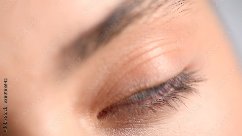 Beautiful human eye close-up. Young Woman Blue one eye macro shoot. Macro Closeup eye blinking and looking, over gray background. Eyelid, iris, Eyesight concept. 4K UHD video. Beautiful human eye close-up. Young Woman Blue one eye macro shoot. Macro Closeup eye blinking and looking, over gray background. Eyelid, iris, Eyesight concept. 4K UHD video.