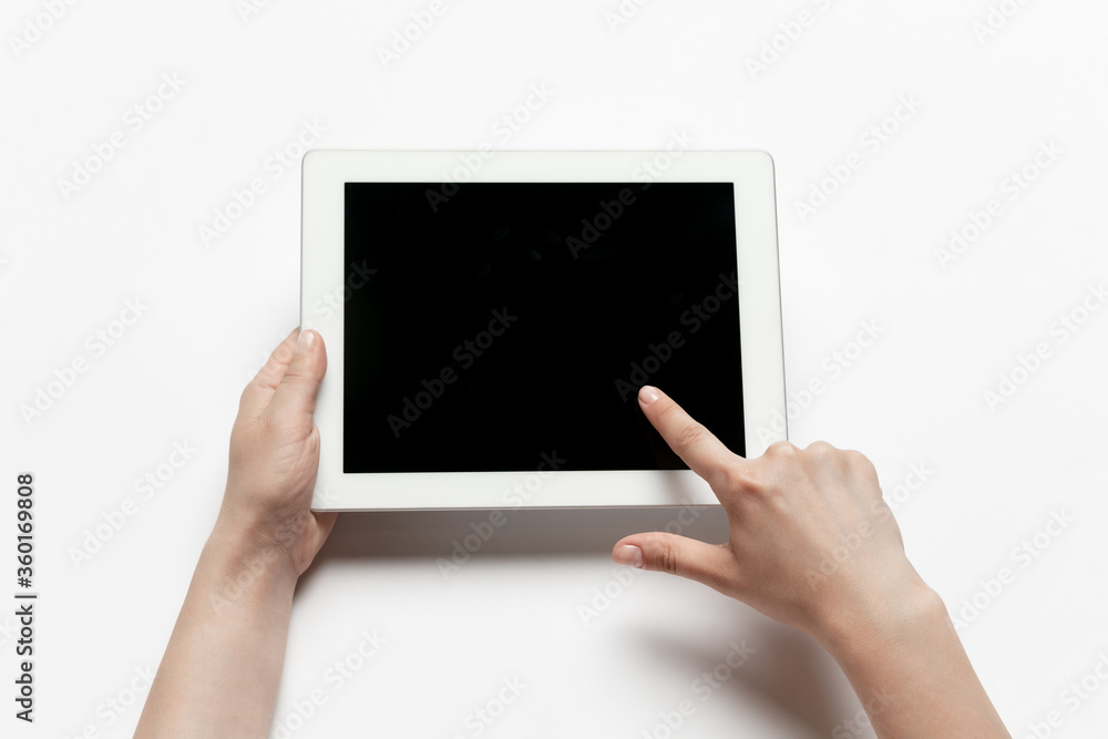 Close up of human hands using tablet isolated on white background. Top view. Copyspace, blank screen. Surfing, online shopping, scrolling, betting, working. Education and business concept. Close up of human hands using tablet isolated on white background. Top view. Copyspace, blank screen. Surfing, online shopping, scrolling, betting, working. Education and business concept.