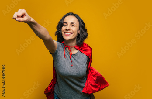 Obraz na plátne I am on my way! A young, beautiful girl, pretending she is a superwoman, and flying in a classic superman pose, dressed casually, but with superman red cloak