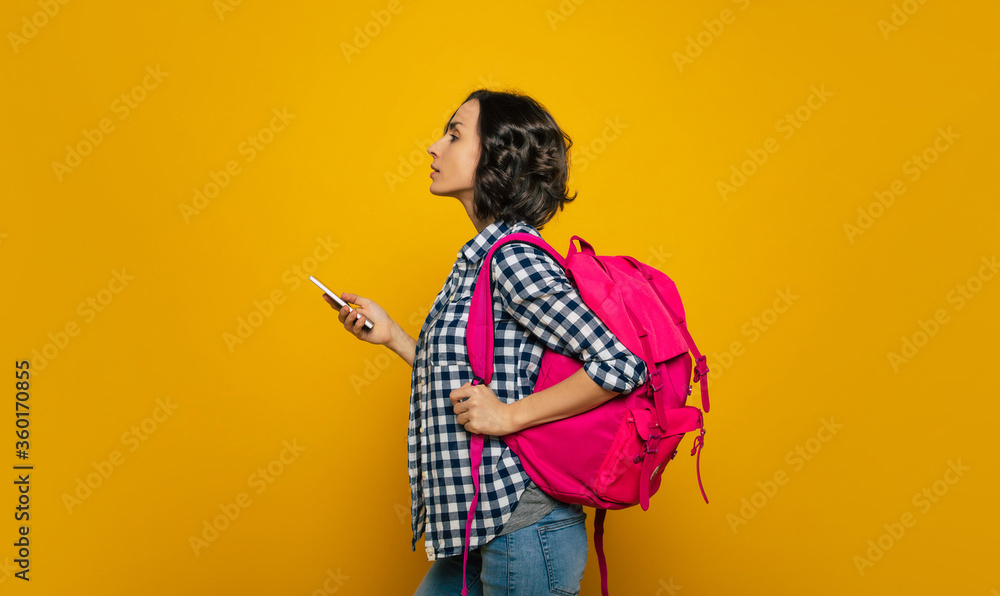 Where is my lecture hall! A half-length photo of a young student, with her cute pink backpack on her one shoulder, turned sideways to check a university stand with her smartphone in her hand. Where is my lecture hall! A half-length photo of a young student, with her cute pink backpack on her one shoulder, turned sideways to check a university stand with her smartphone in her hand.
