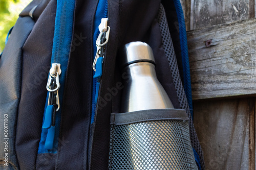 Metal flask, bottle, thermos inside a mesh pocket of a backpack