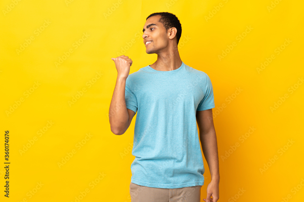 African American man over isolated background pointing to the side to present a product African American man over isolated background pointing to the side to present a product