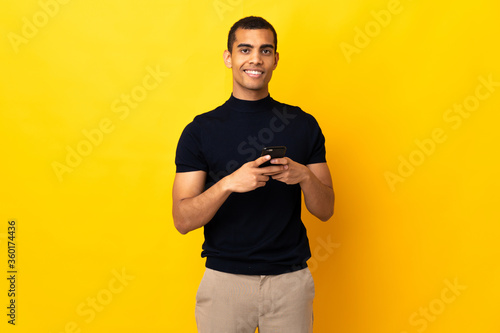 African American man over isolated background sending a message with the mobile