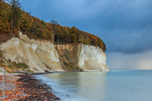 Chalk cliffs in the Pirate Bay. Autumn mood on the island of Ruegen. Baltic Sea with stony beach on the coast in the morning. Trees with foliage in the Jasmund National Park on the Baltic Sea