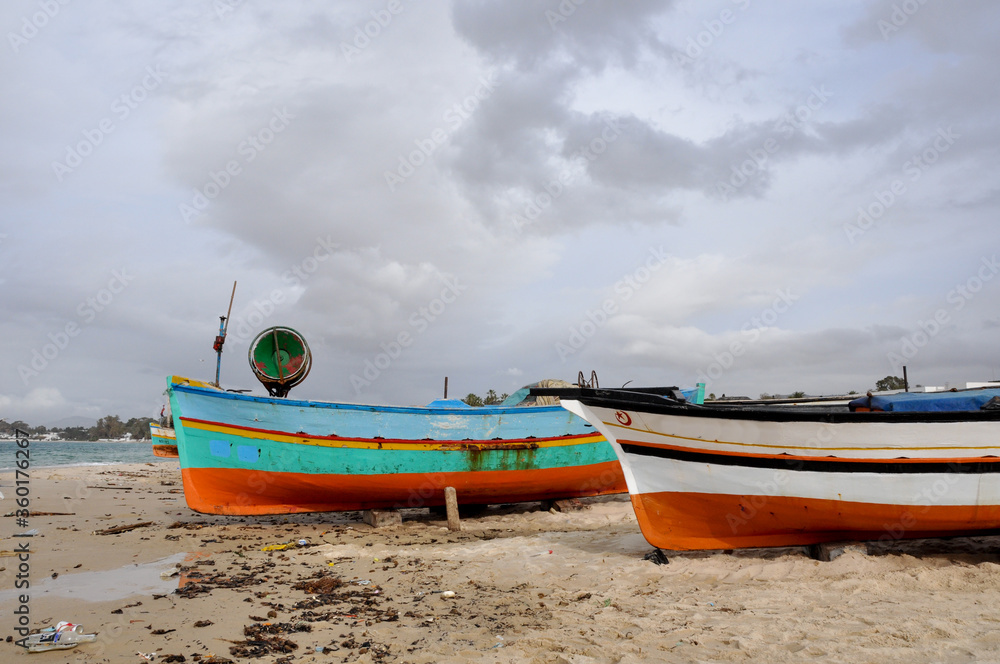 Naklejka premium Hammamet, Tunisia- February 07, 2009: Tunisian Fishing boats on the beach with traditional colors.