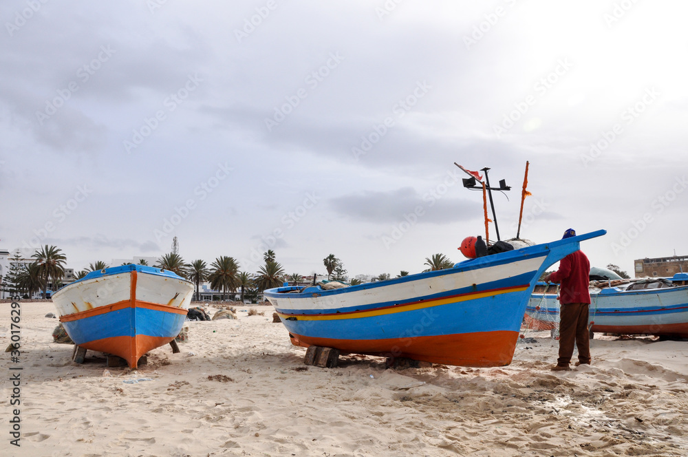 Naklejka premium Hammamet, Tunisia- February 07, 2009: Tunisian Fishing boats on the beach with traditional colors.