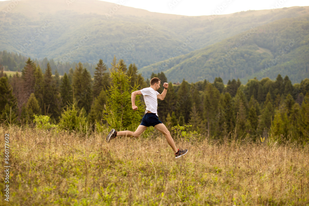 Fototapeta premium Running fitness man sprinting outdoors with beautiful mountains landscape on background. Runner training for marathon.