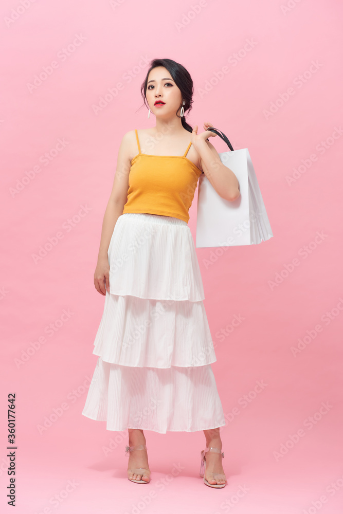 Full length portrait of smiling young woman with shopping bags over pink background. Full length portrait of smiling young woman with shopping bags over pink background.