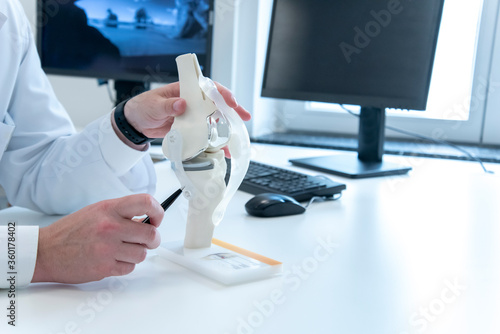 Arzt erklärt Patient etwas am Modell eines Kniegelenks