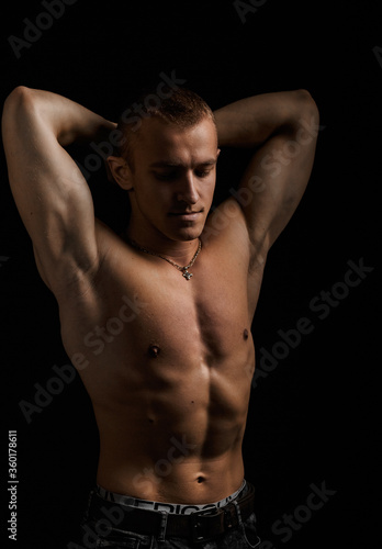 Young muscular bodybuilder posing over black background.