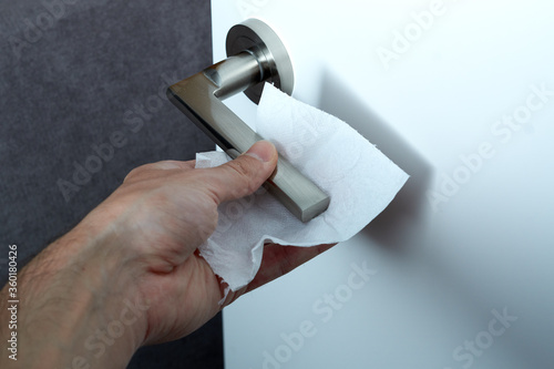 Close up of hand cleaning and disinfecting door handle surface with antiseptic