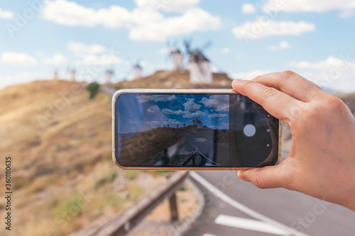 Taking a picture of the traditional windmills with the mobile phone. Traditional windmills in the background.