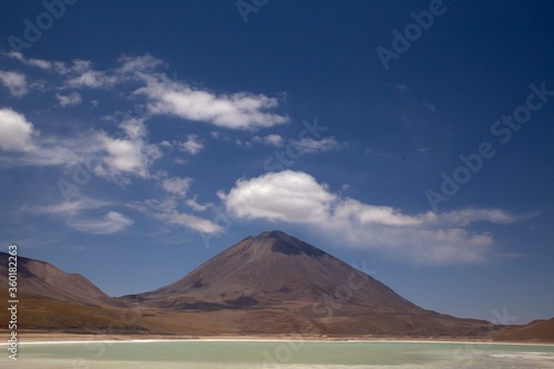 Mountain with a cloud over it on top and a green lagoon. Volcano and lake landscape. Licancabur, Chile and Bolivia natural border