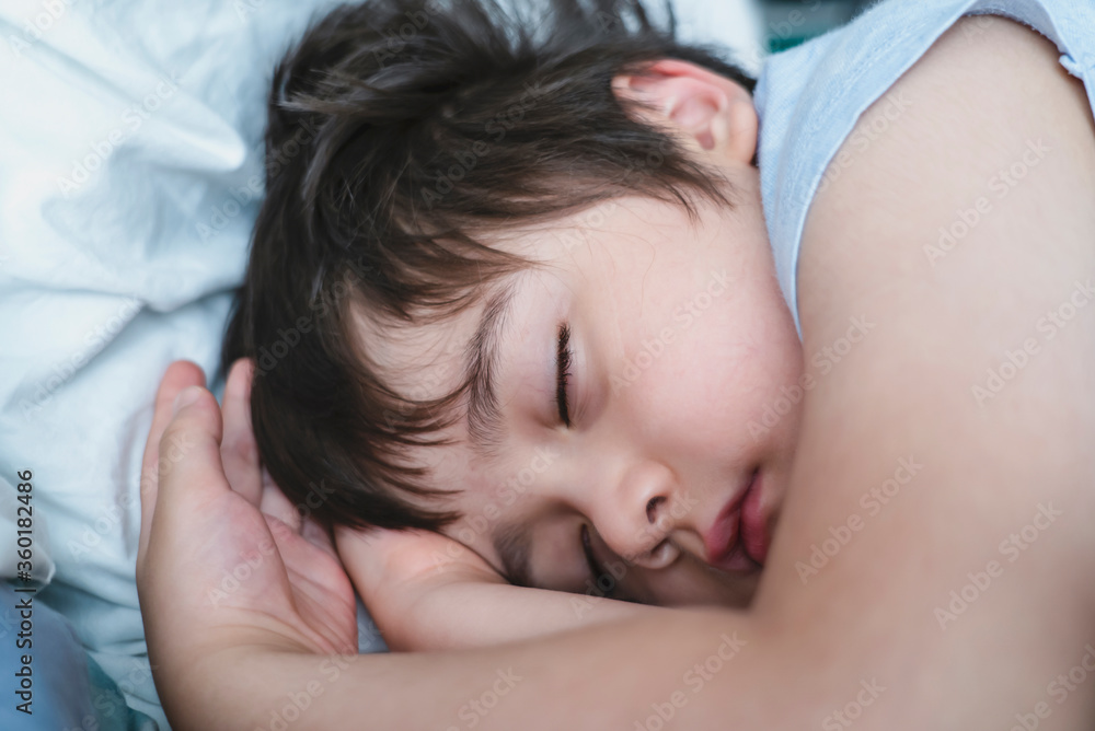 Adorable kid deep sleep in bed in the morning, Child  sleeping on bed. Little boy taking a peaceful nap, Children health care concep
