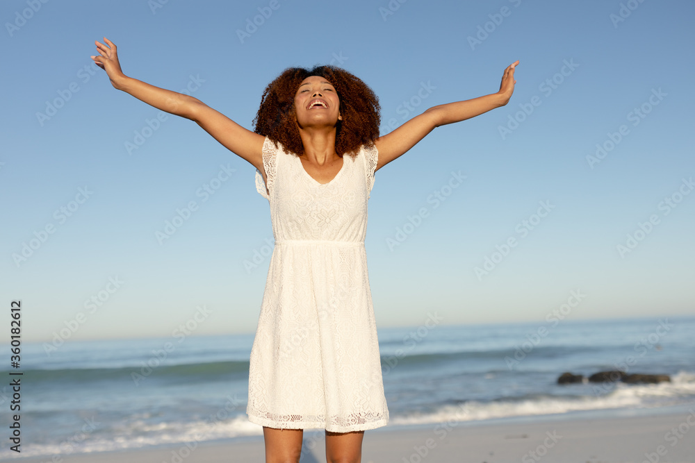 A mixed race woman with her arms outstretched on beach on a sunny day A mixed race woman with her arms outstretched on beach on a sunny day