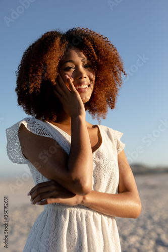 Mixed race woman with her hand on her face on beach on a sunny day