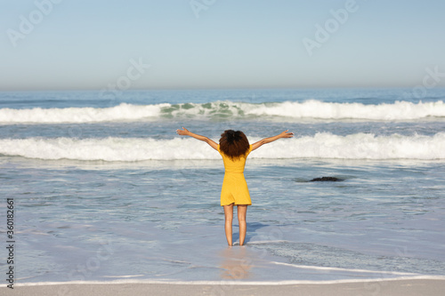 Canvastavla A mixed race woman with her arms outstretched on beach on a sunny day