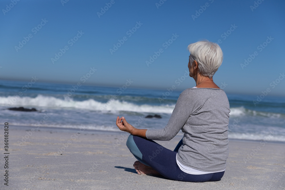 Senior Caucasian woman meditating at the beach.