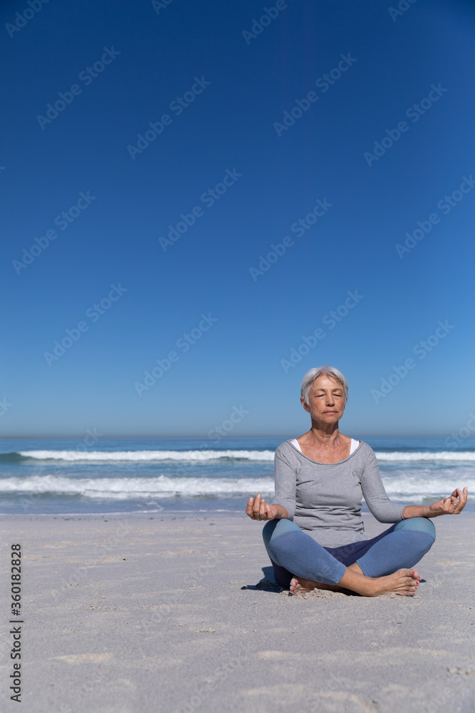Senior Caucasian woman meditating at the beach.