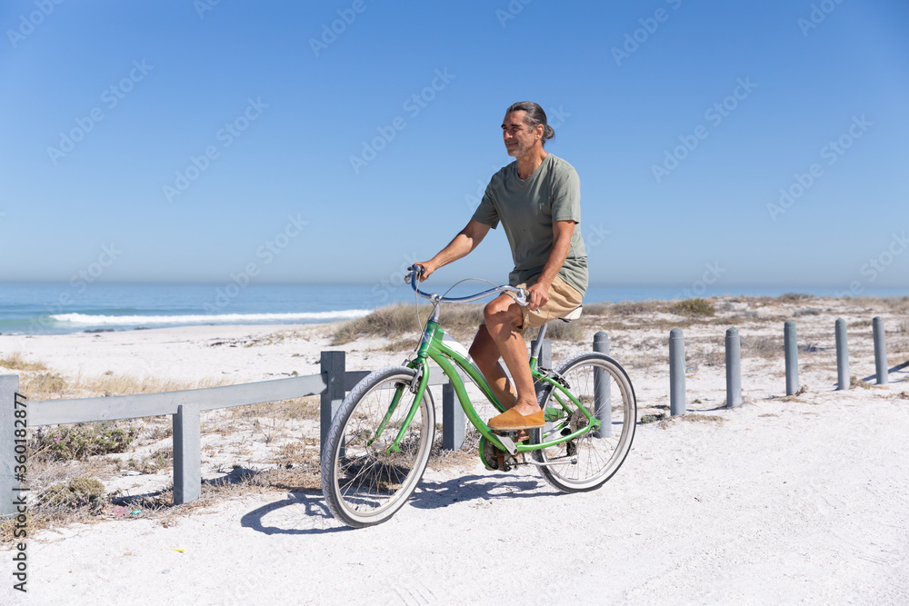 Senior Caucasian man riding a bike at the beach Senior Caucasian man riding a bike at the beach