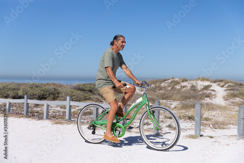 Senior Caucasian man riding a bike at the beach