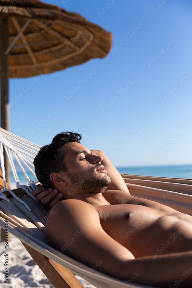 Caucasian man lying on a hammock at the beach.