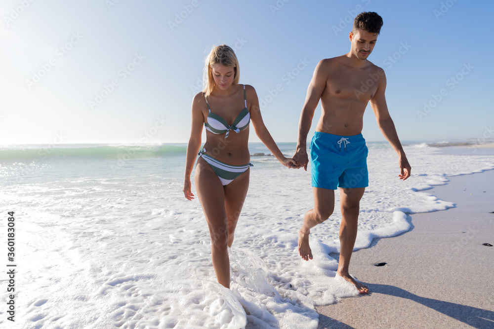 Caucasian couple standing in water at the beach.