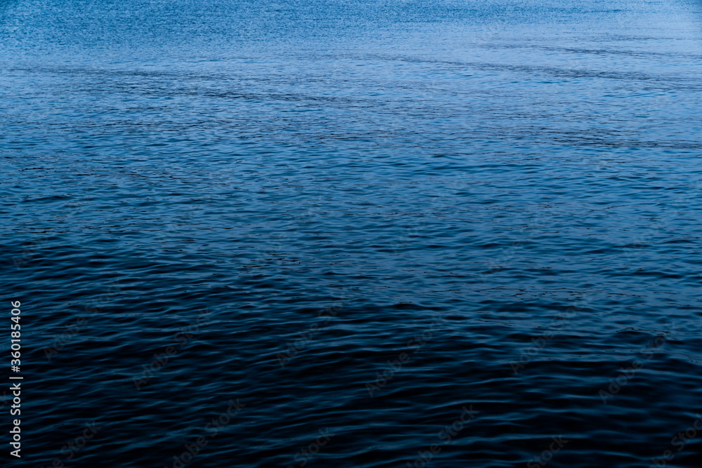 Background of a calm blue sea with the texture of the waves in the blue hour at sundown. Concept of climate crisis and refugee crisis in the Mediterranean Sea. Background of a calm blue sea with the texture of the waves in the blue hour at sundown. Concept of climate crisis and refugee crisis in the Mediterranean Sea.