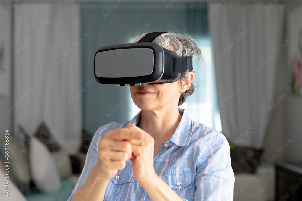 Senior Caucasian woman putting on a VR headset at home Senior Caucasian woman putting on a VR headset at home